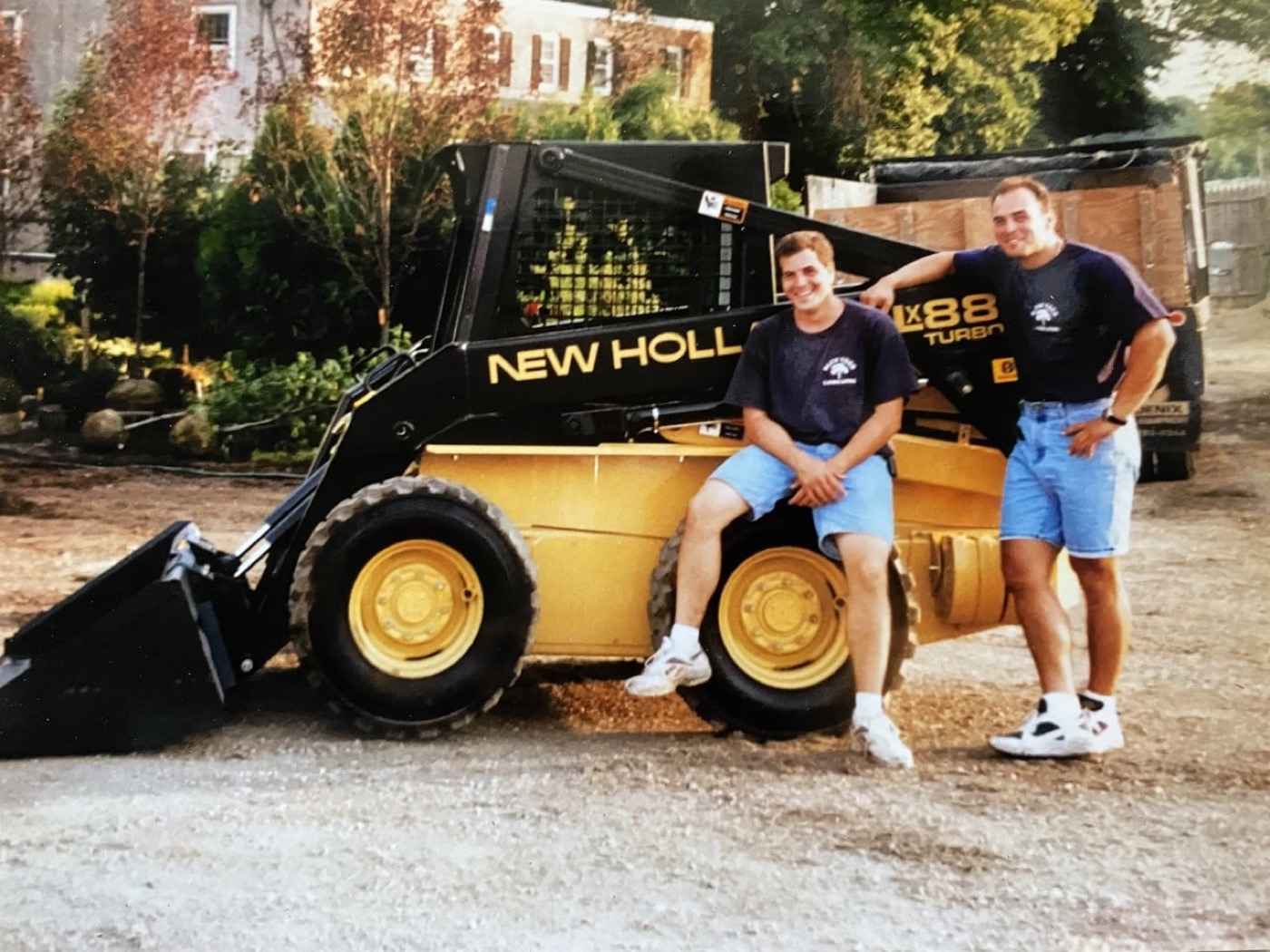 Two young Blue Tree crew members with a skid-steer loader in the company's early days